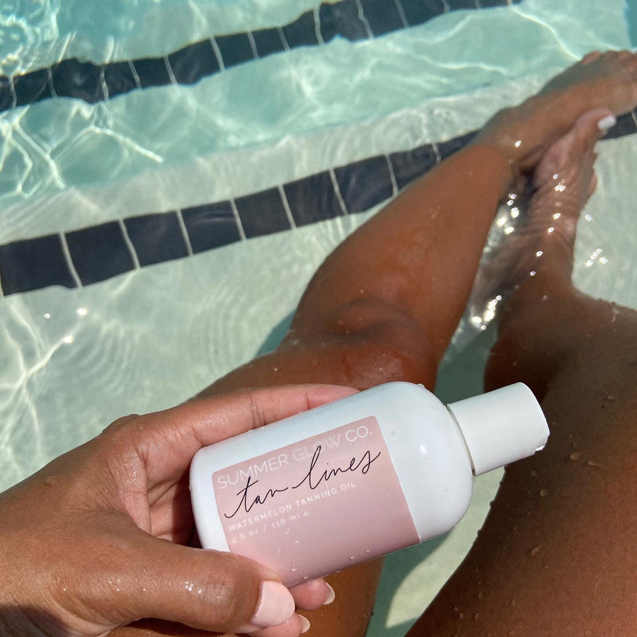 tan women holding tanning oil in pool